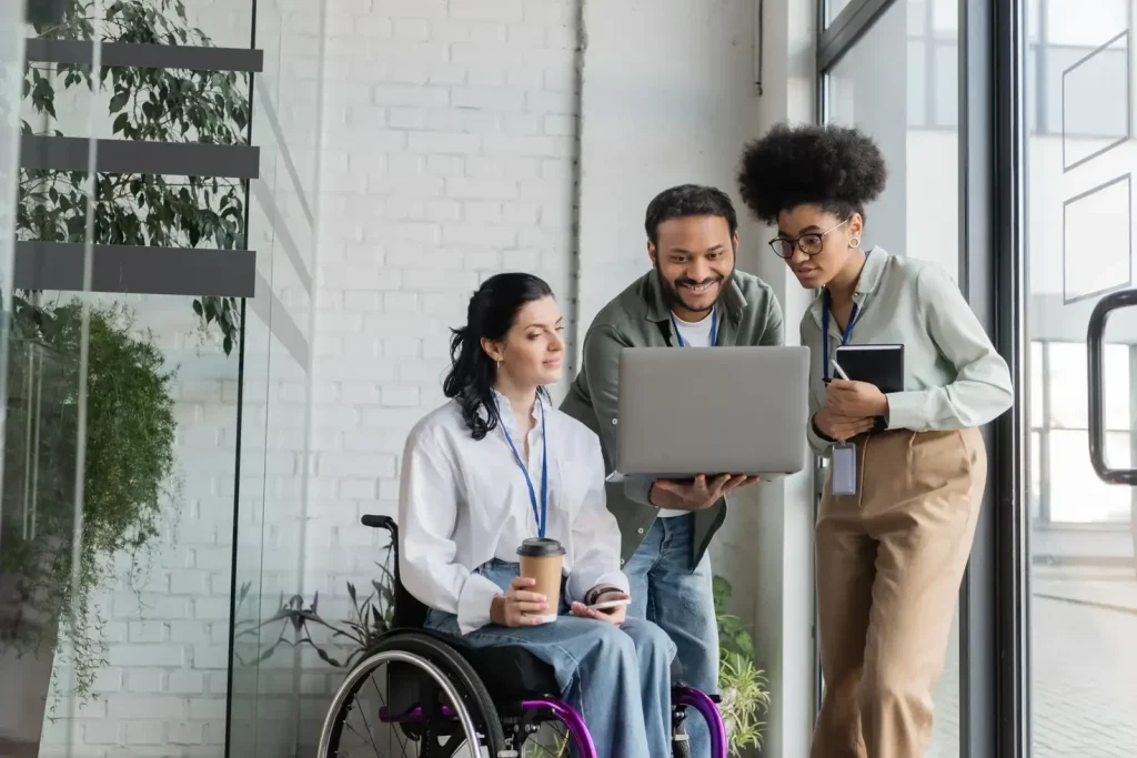 Three young professionals - one of them in a wheelchair - looking over a referral they've received at Minto Care