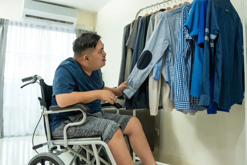 Young man in wheelchair selecting which clothes he is going to wear from his wardrobe